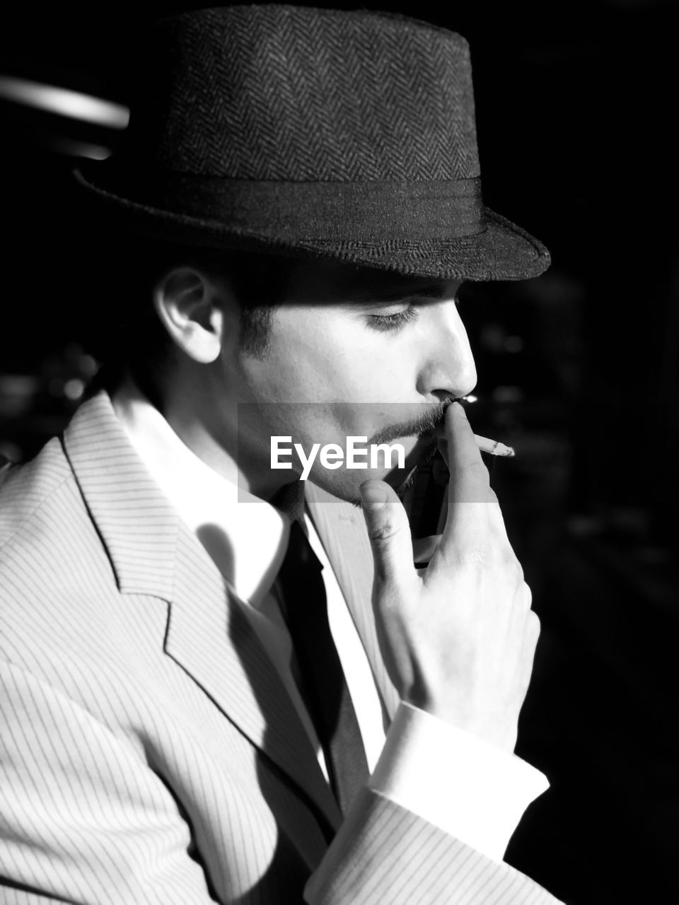 Close-up of man smoking against black background