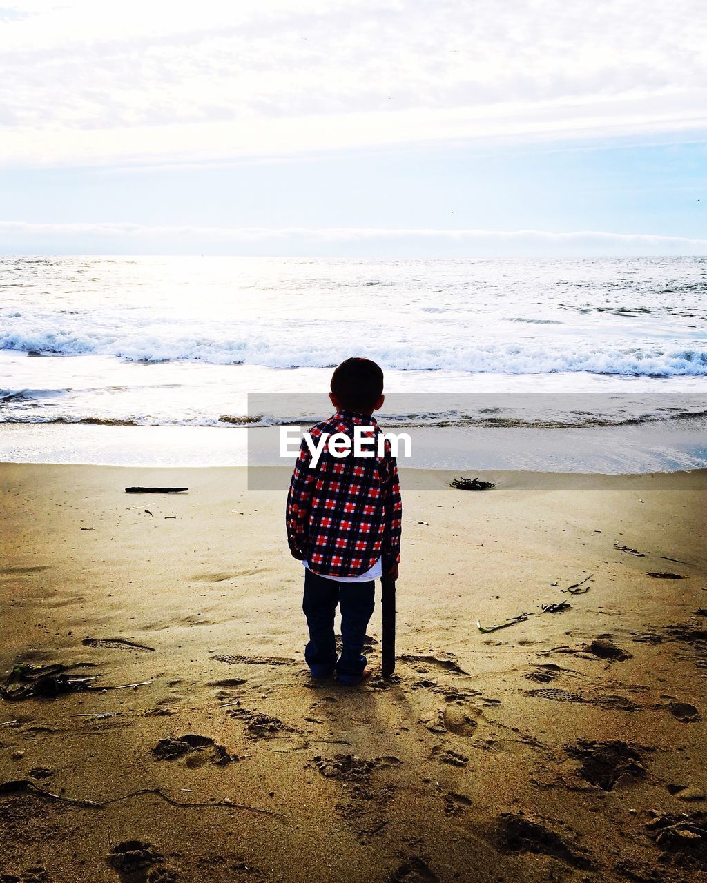 FULL LENGTH REAR VIEW OF BOY STANDING ON BEACH