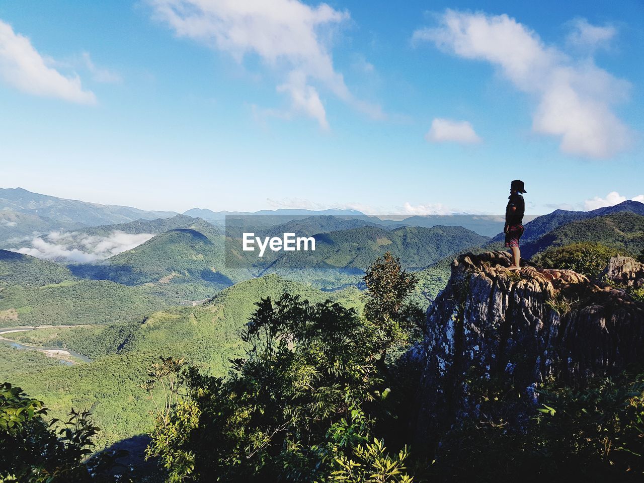 Side view of man standing on mountain against blue sky