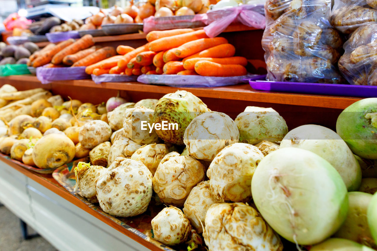 Celery, turnip, carrots, onions, roots and other various vegetables are sold on market shelves.