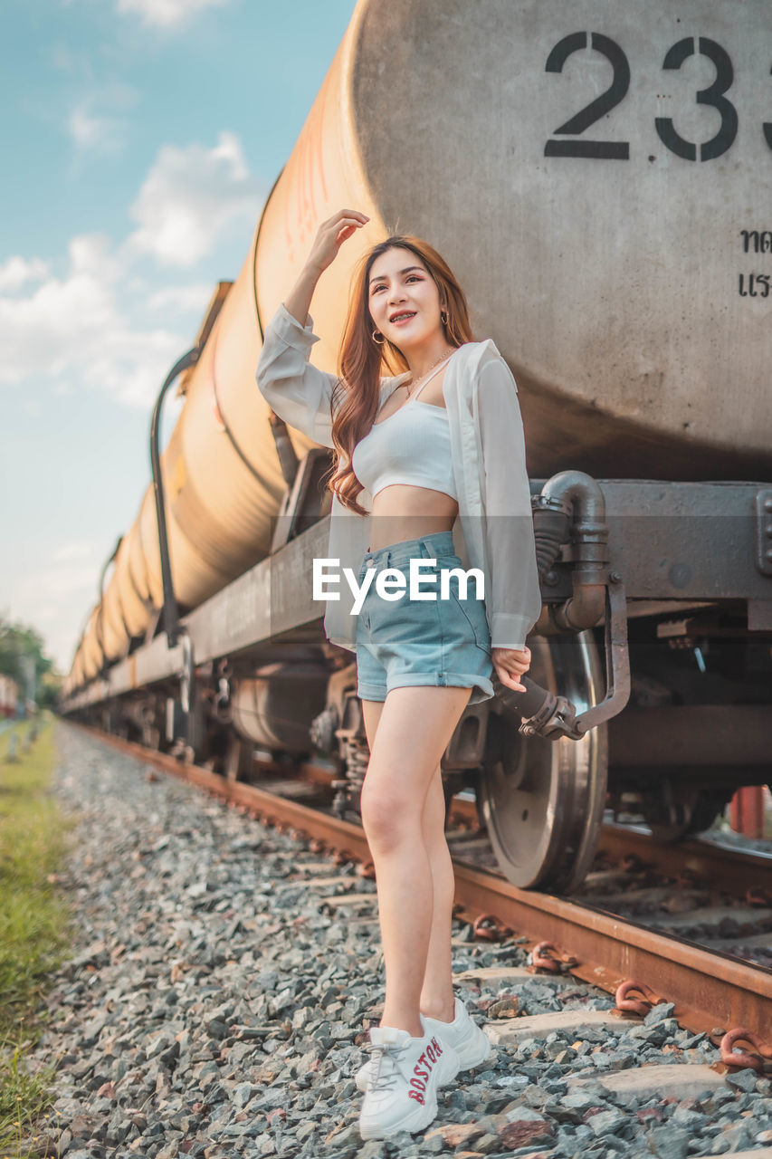 Portrait of smiling young woman standing on railroad track