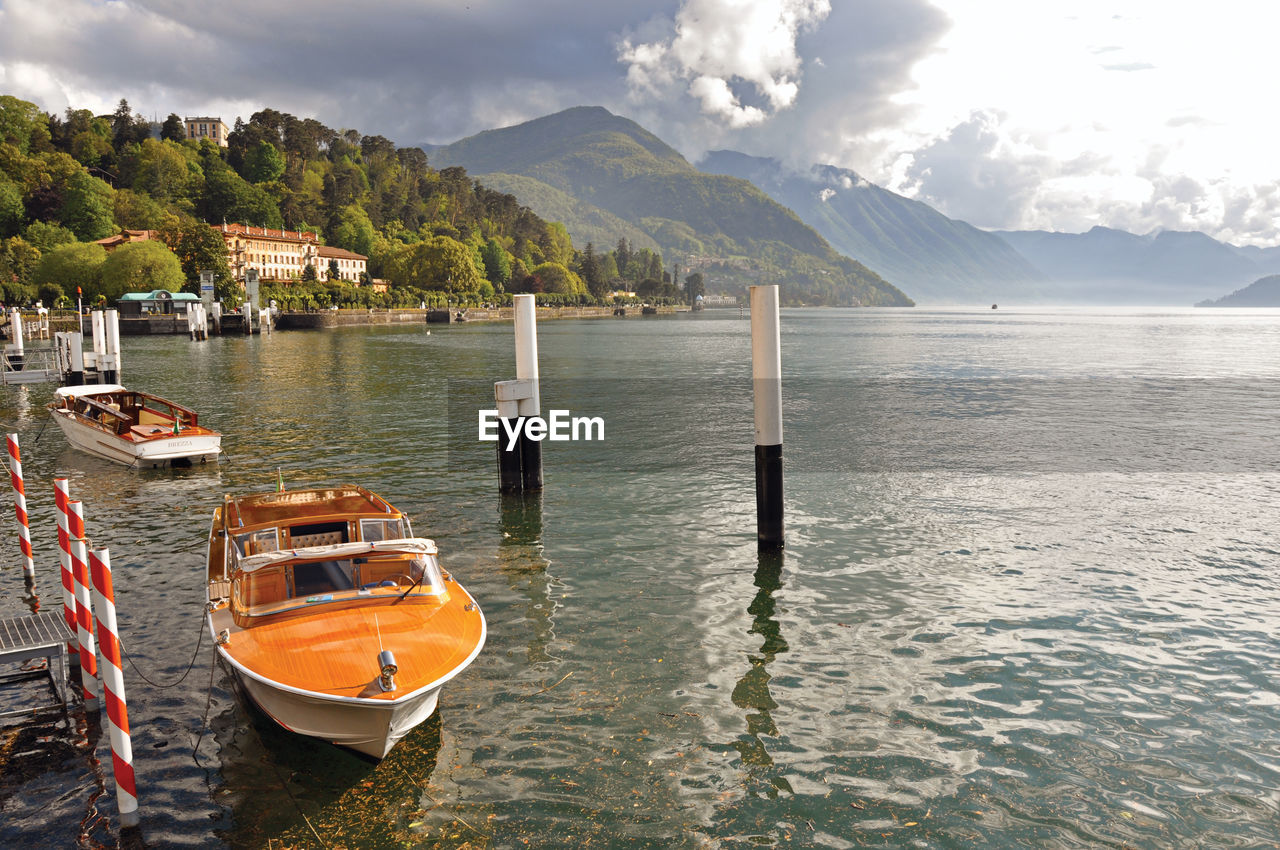 Lake como in a cloudy day with motorboat and harbor in bellagio, italy.