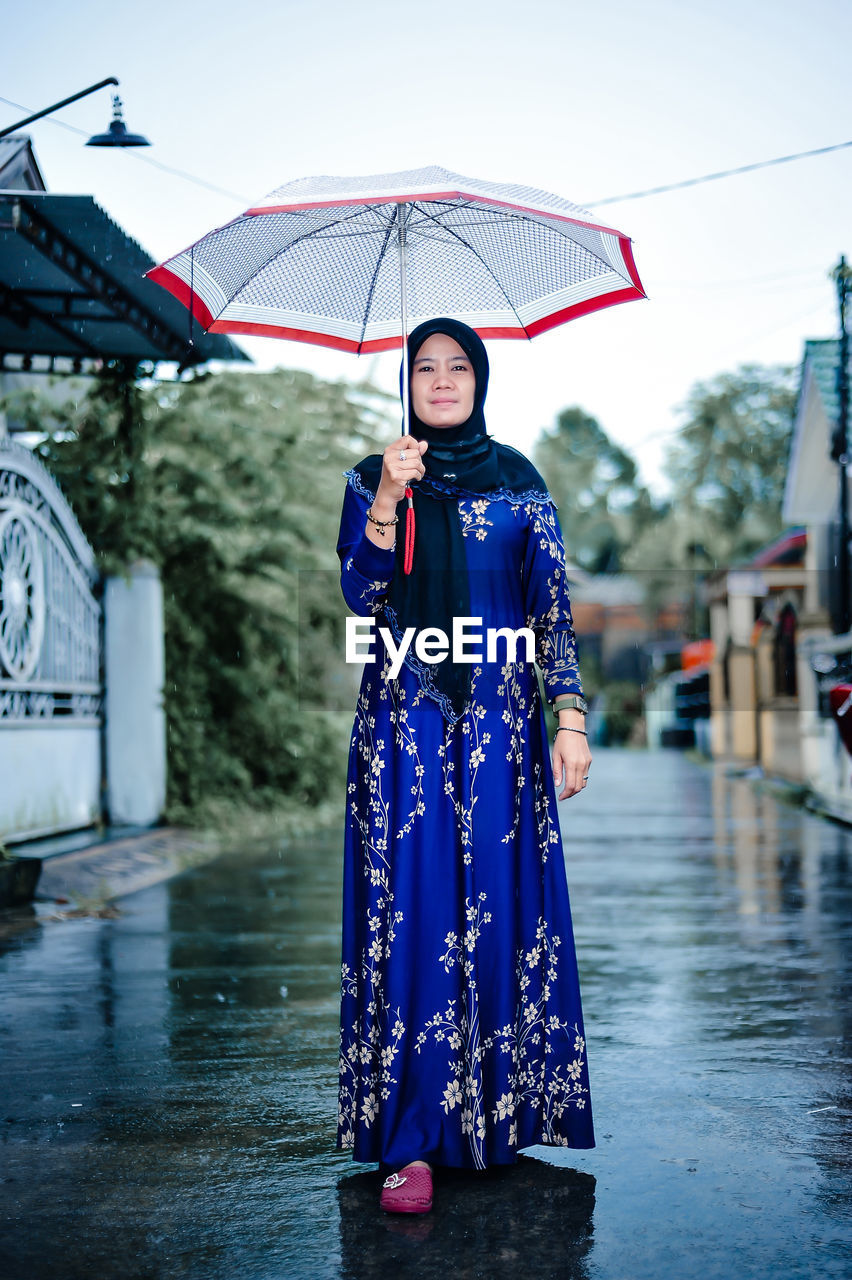 Portrait of woman with umbrella walking on street