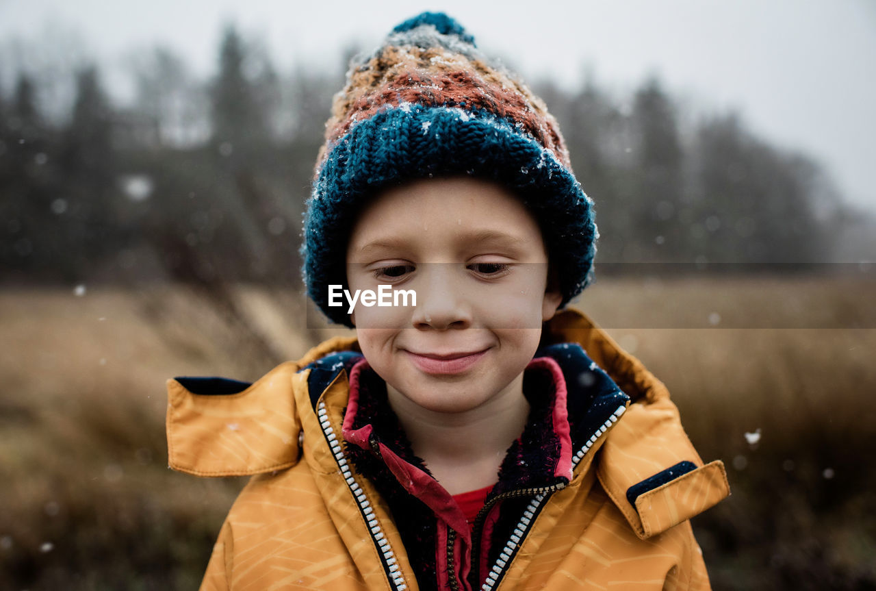 Boy looking out a window holding a cereal bowl at christmas