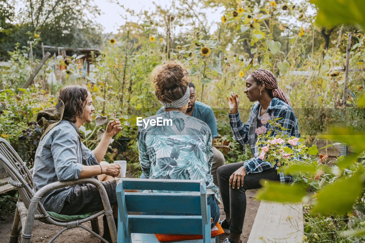 Male and female farmers having coffee while sitting in community garden