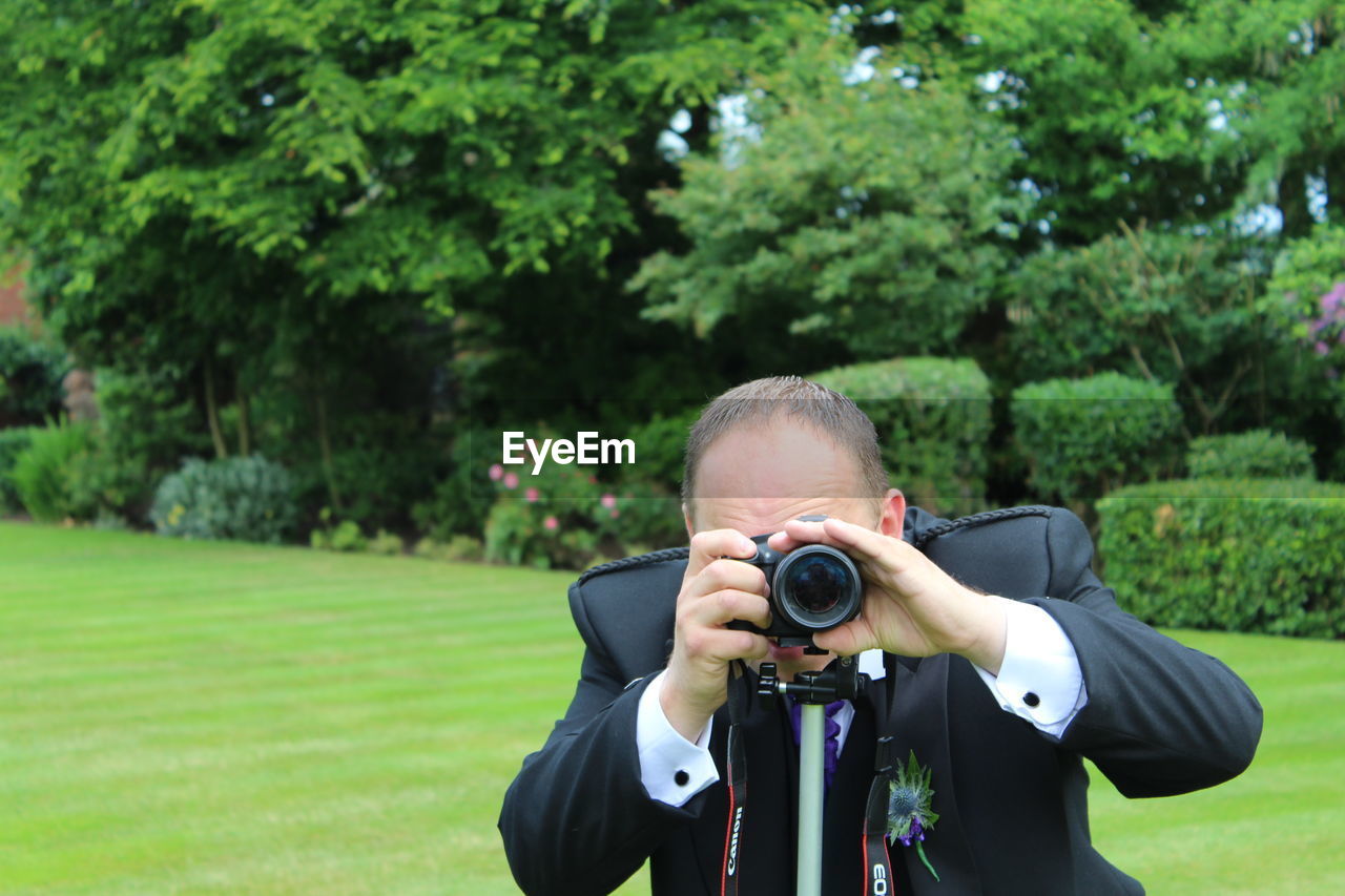 Man photographing through digital camera in garden