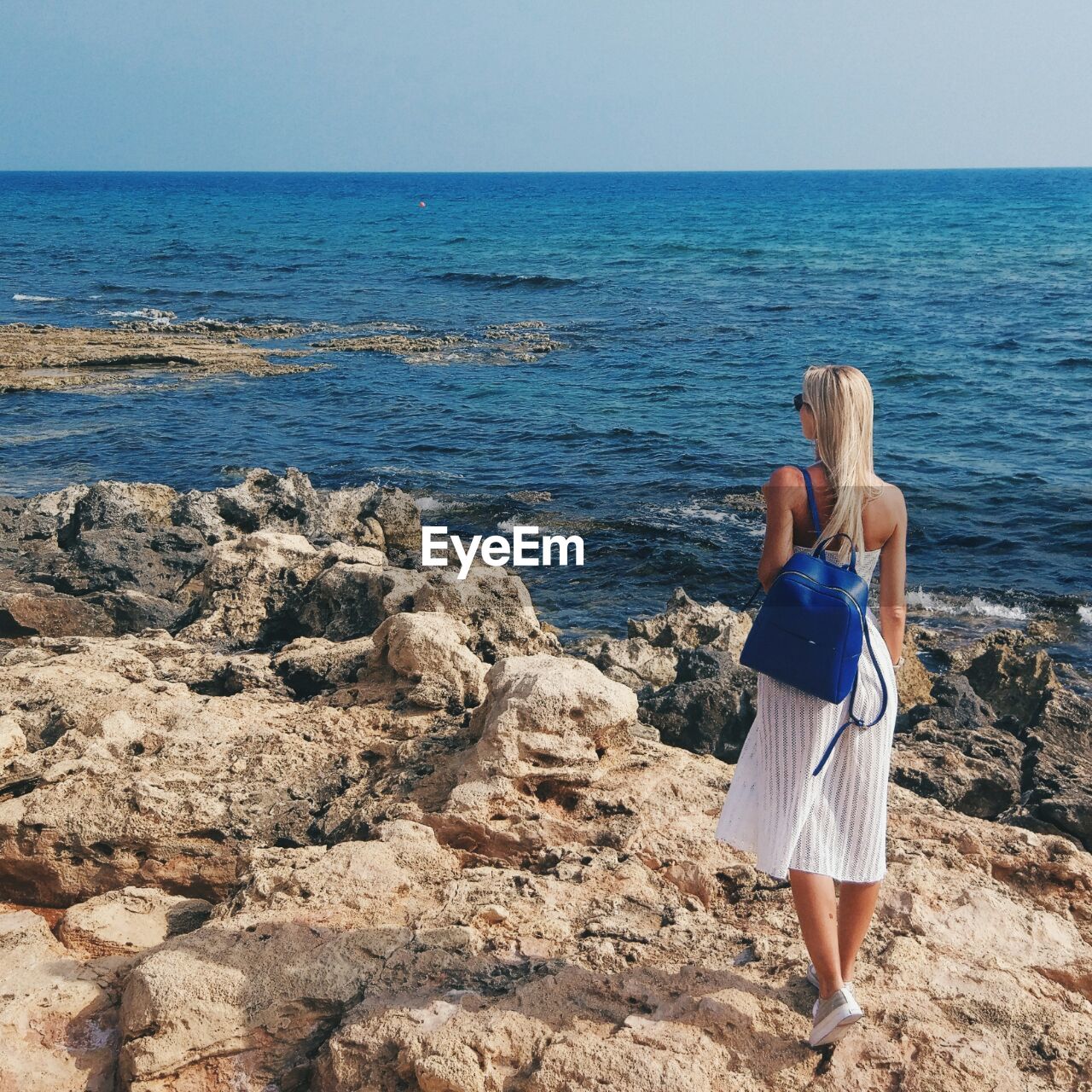 Rear view of woman standing on beach against clear sky