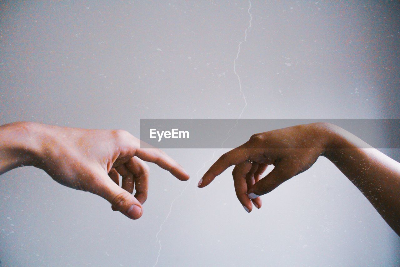 Cropped hands of women reaching against sky