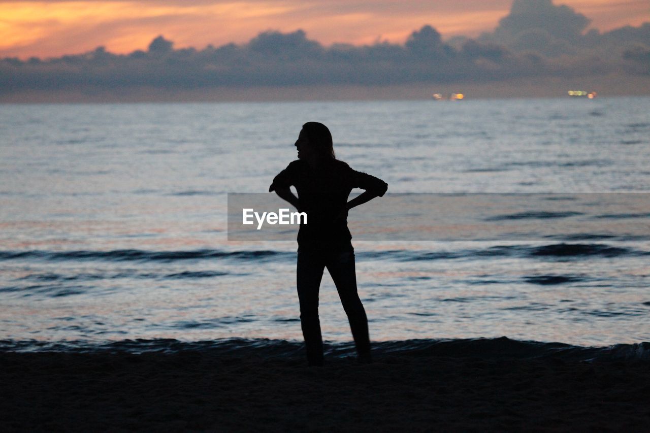 Man standing on sea shore during sunset