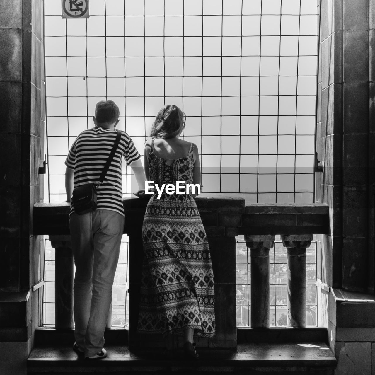Rear view of man and woman standing by railing
