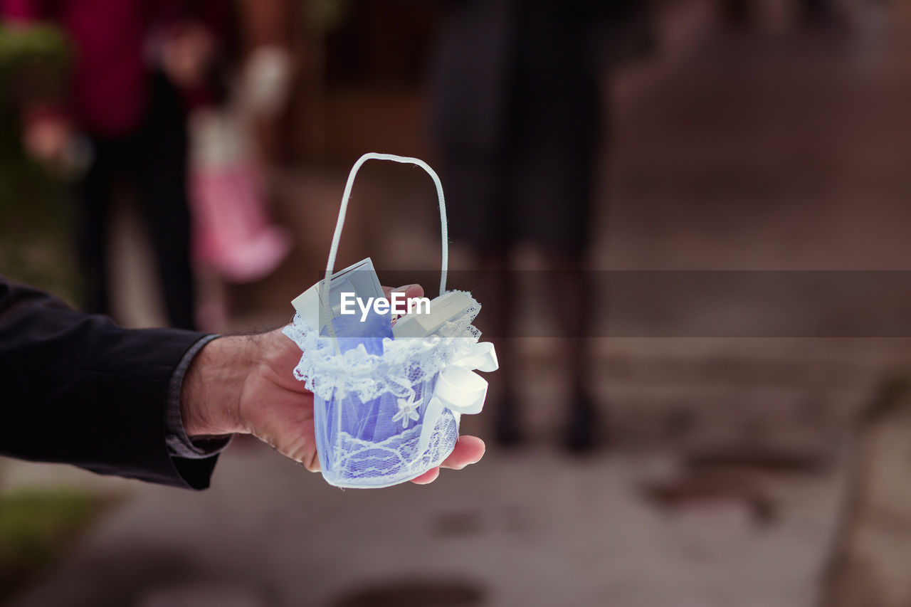 Cropped hand of man holding wedding rings outdoors