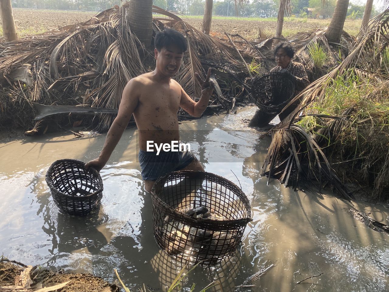 Man and his mother catching fish in the ditch