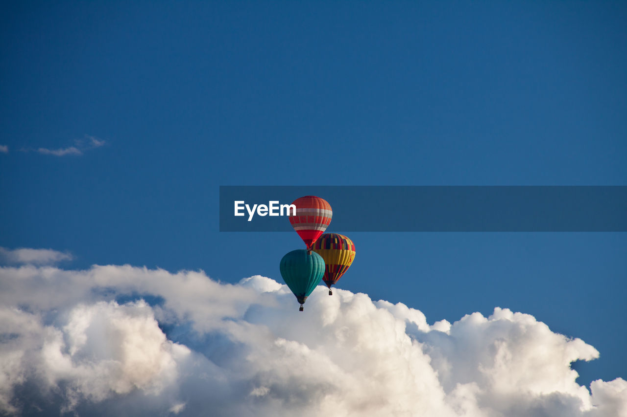 Low angle view of hot air balloons flying in blue sky