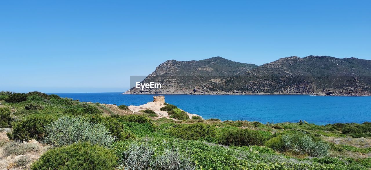 Scenic view of porto ferro la torretta against clear blue sky