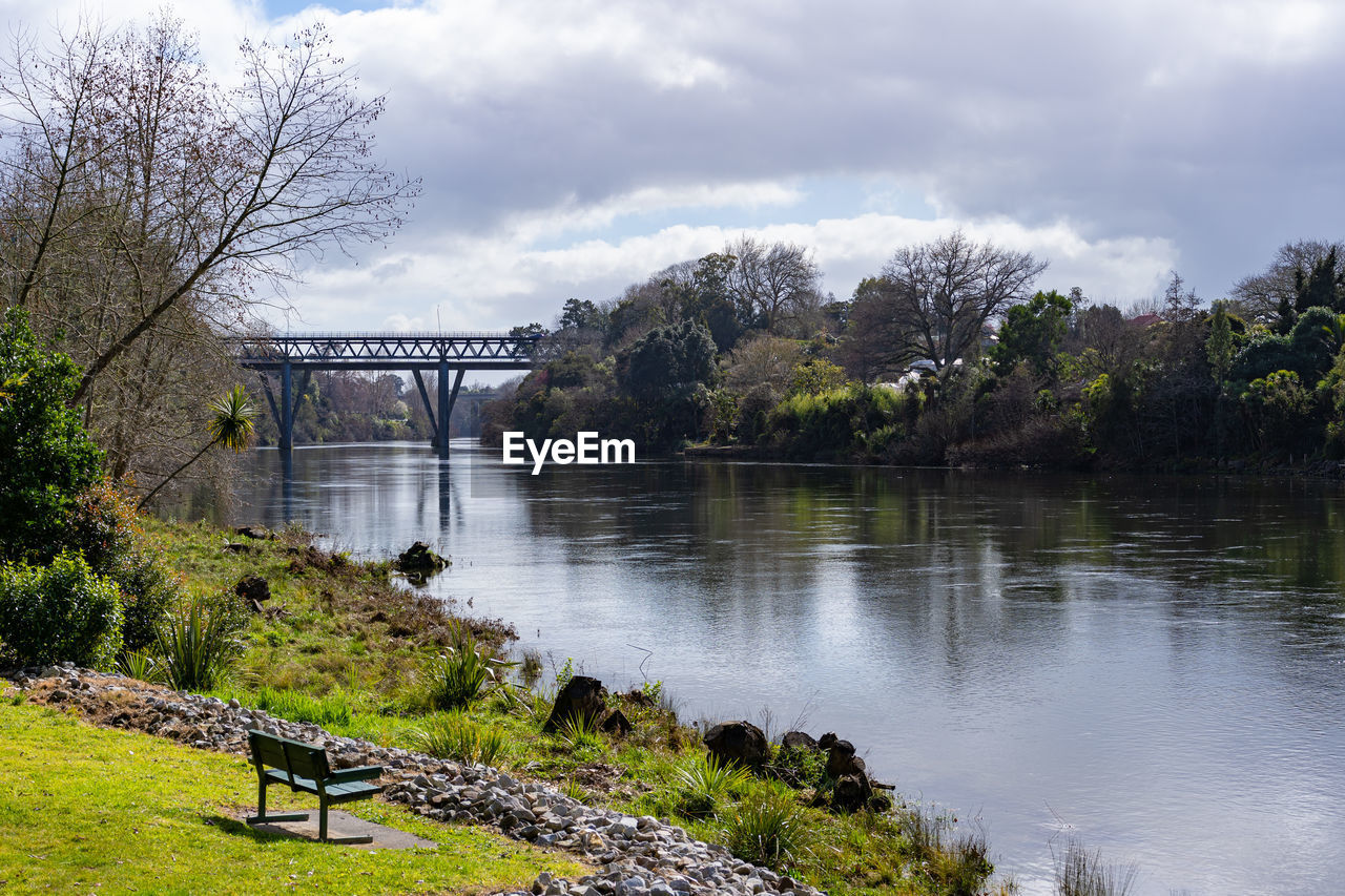 BRIDGE OVER RIVER BY TREES AGAINST SKY