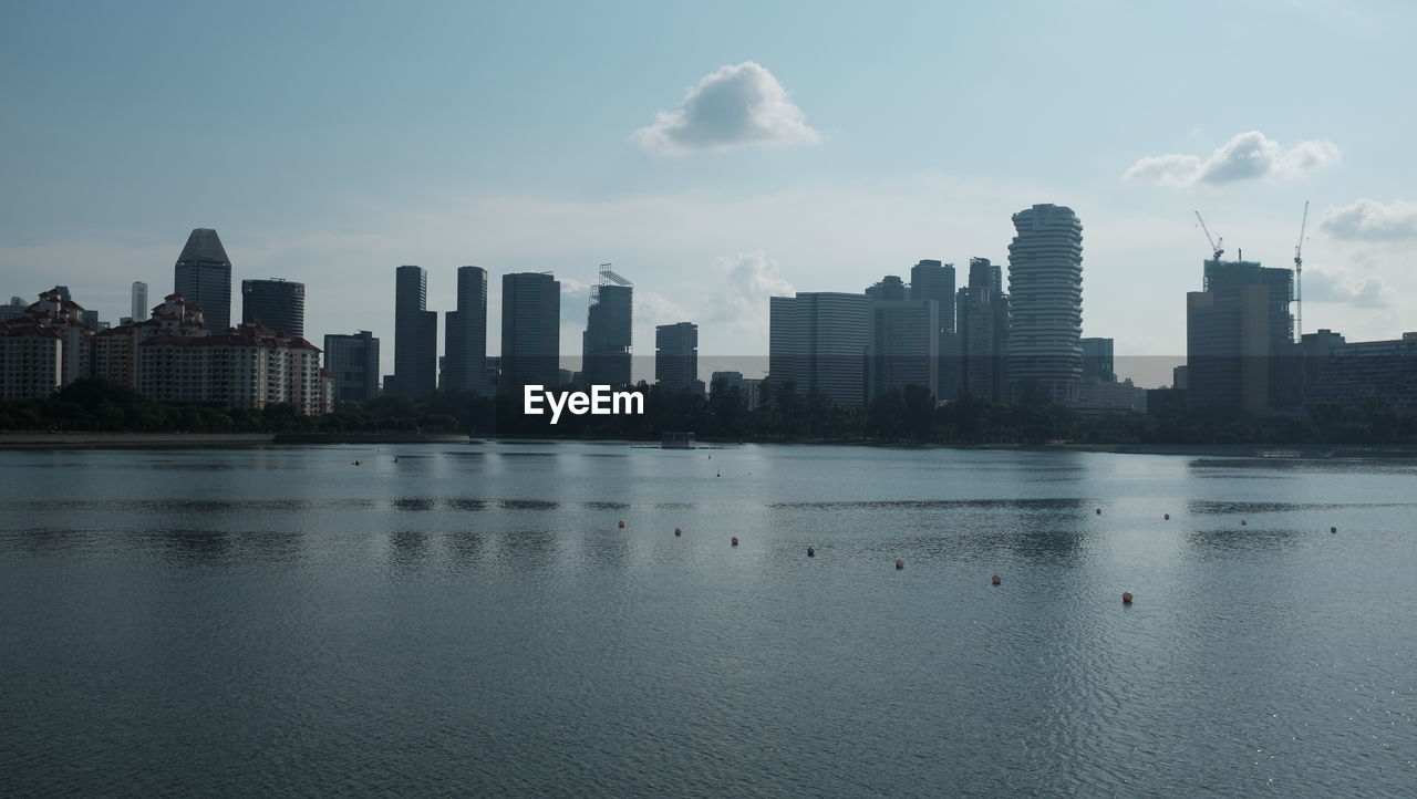 Sea and buildings in city against sky