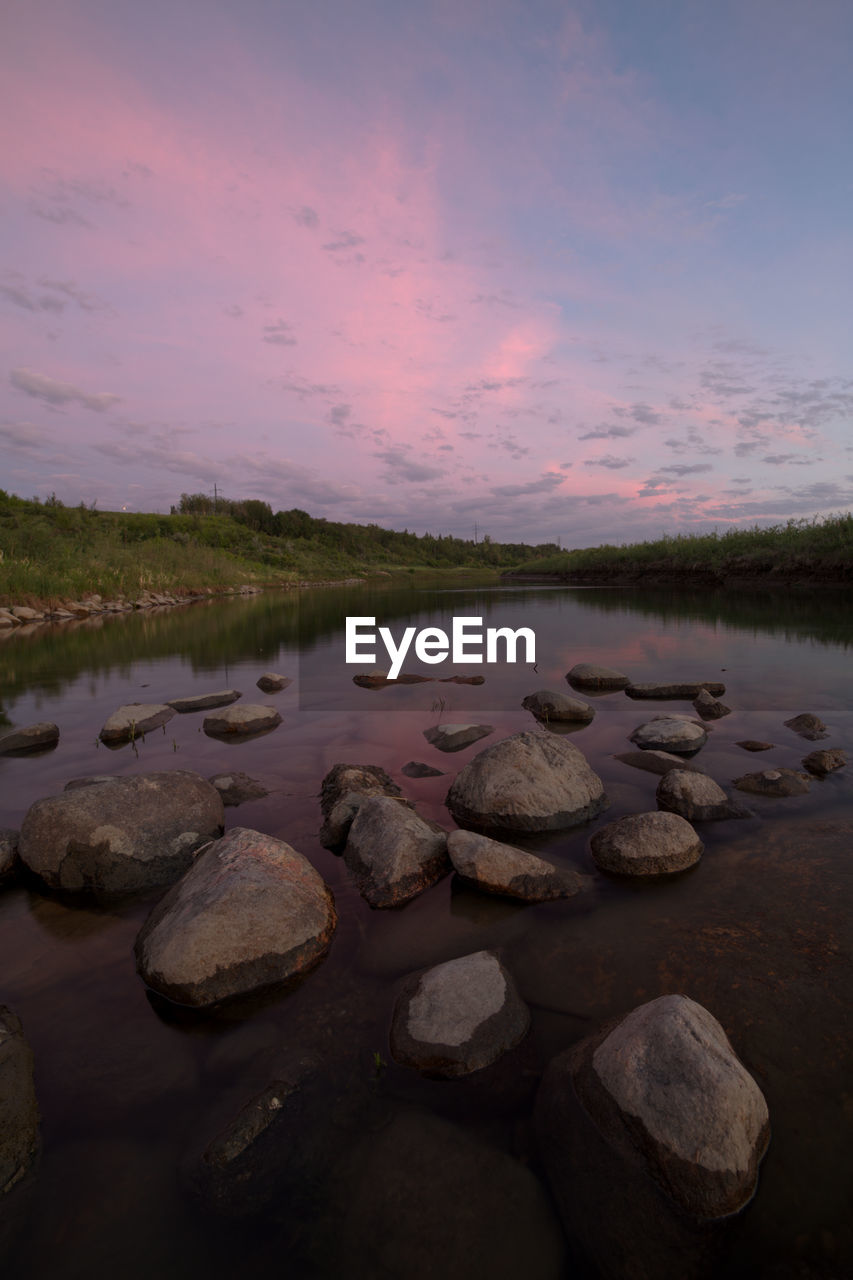 ROCKS AT LAKE AGAINST SKY DURING SUNSET