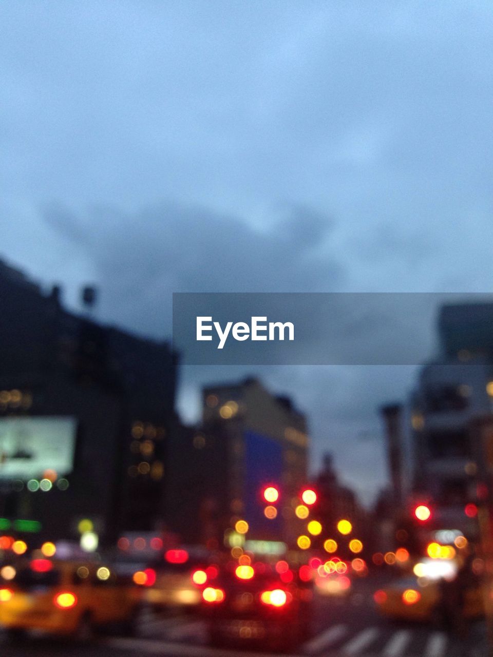 Defocused image of car on illuminated road in city against sky