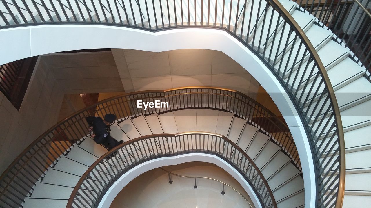 Directly above view of man walking on spiral staircase in building