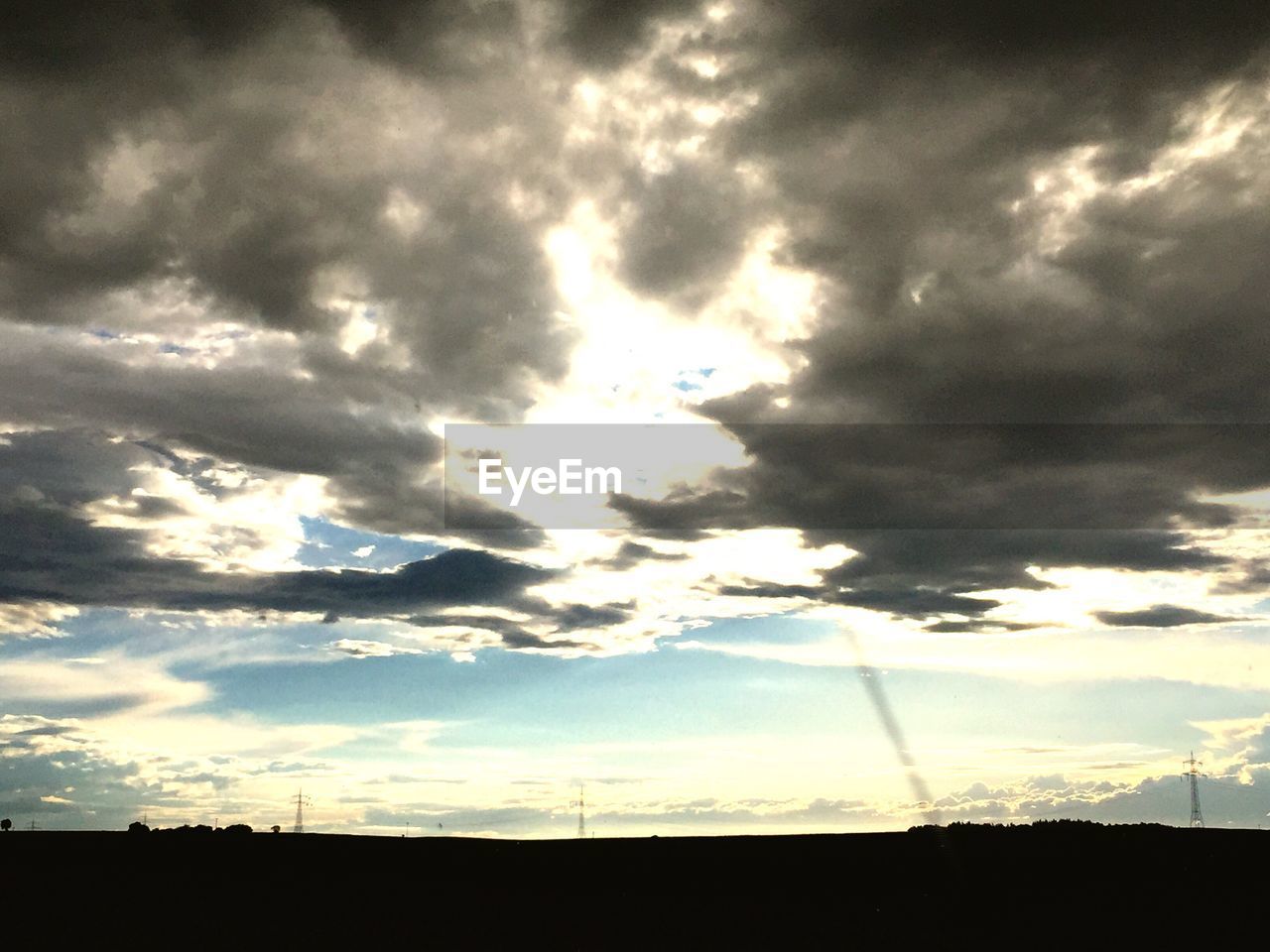 LOW ANGLE VIEW OF CLOUDS OVER SILHOUETTE LANDSCAPE