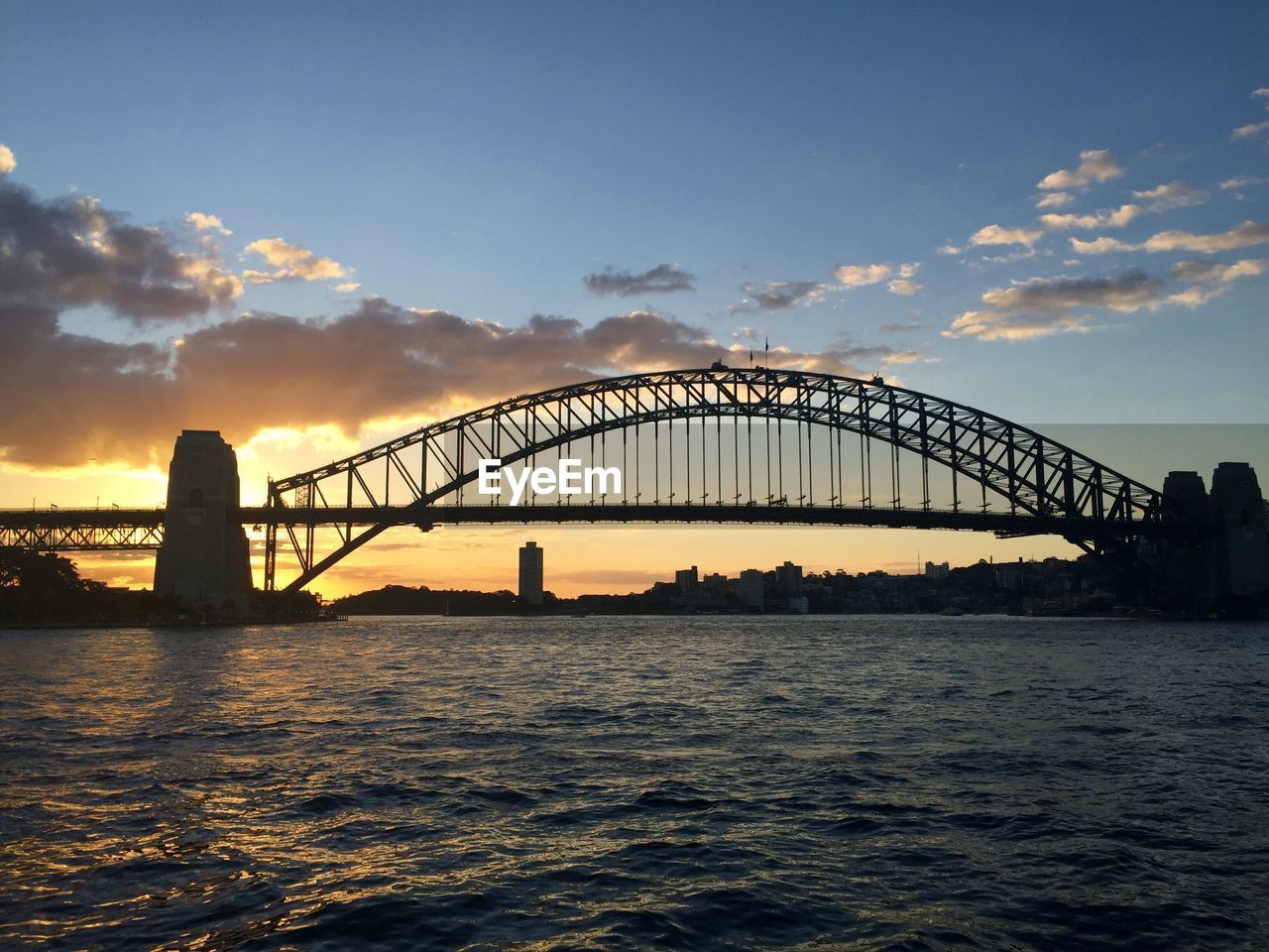 View of suspension bridge over river during sunset