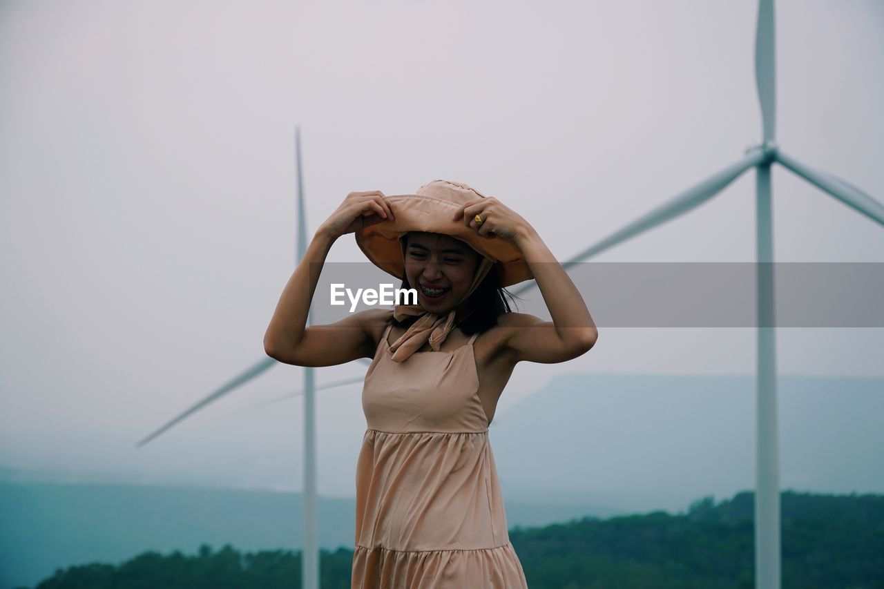 Portrait of young woman standing against sky