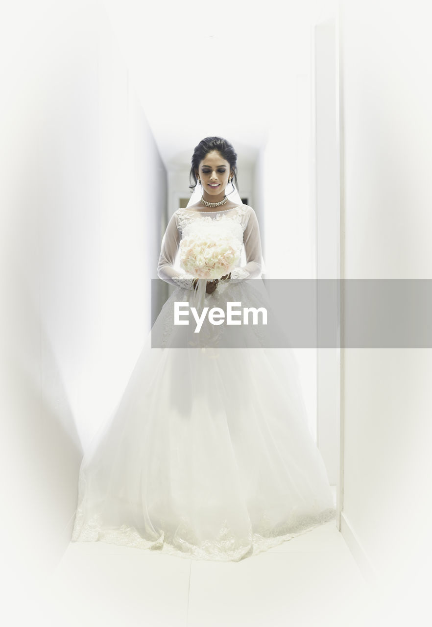 Bride wearing dress while standing in corridor