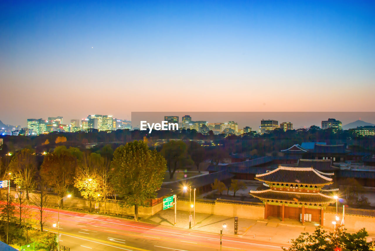 ILLUMINATED CITYSCAPE AGAINST SKY AT SUNSET