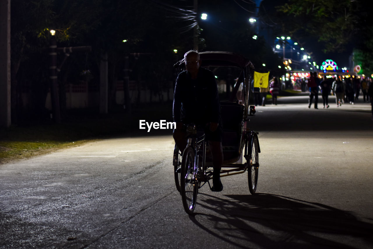Full length of man cycling bicycle cart on road at night