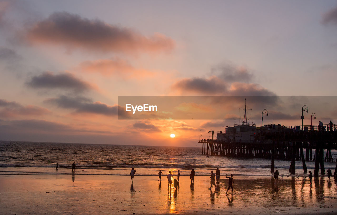 Crowd on beach at santa monica pier during sunset