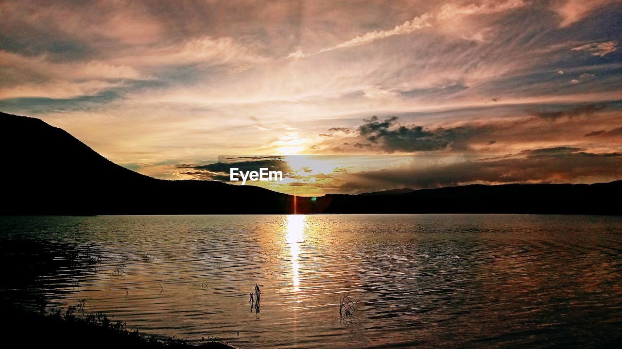 SCENIC VIEW OF LAKE BY SILHOUETTE MOUNTAINS AGAINST SKY