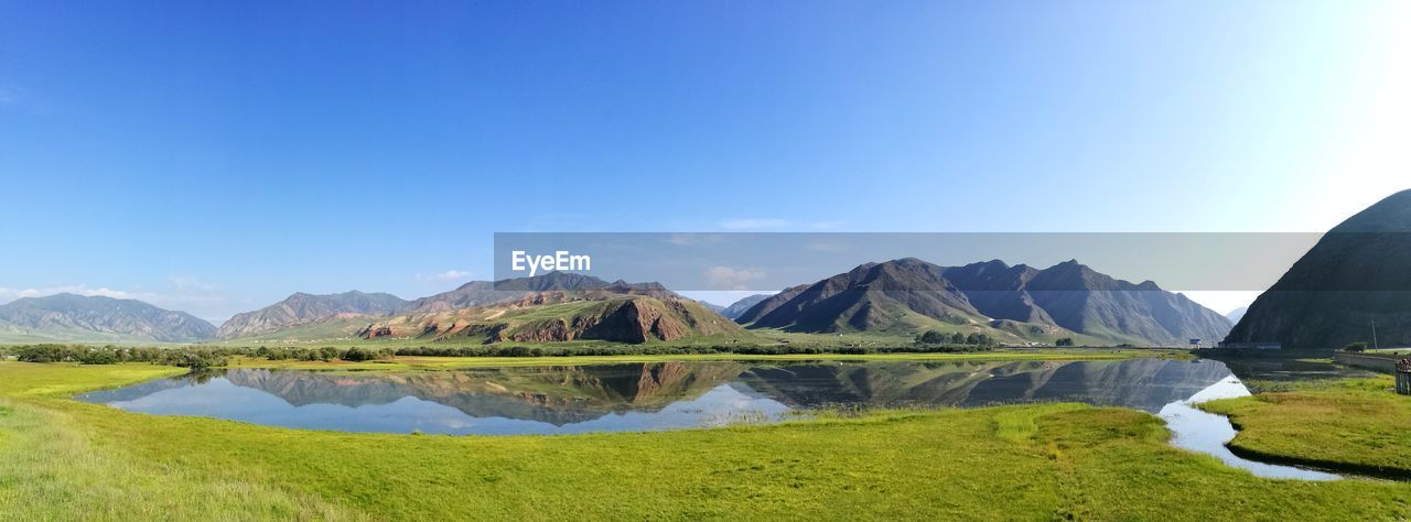 Scenic view of lake and mountains against clear blue sky