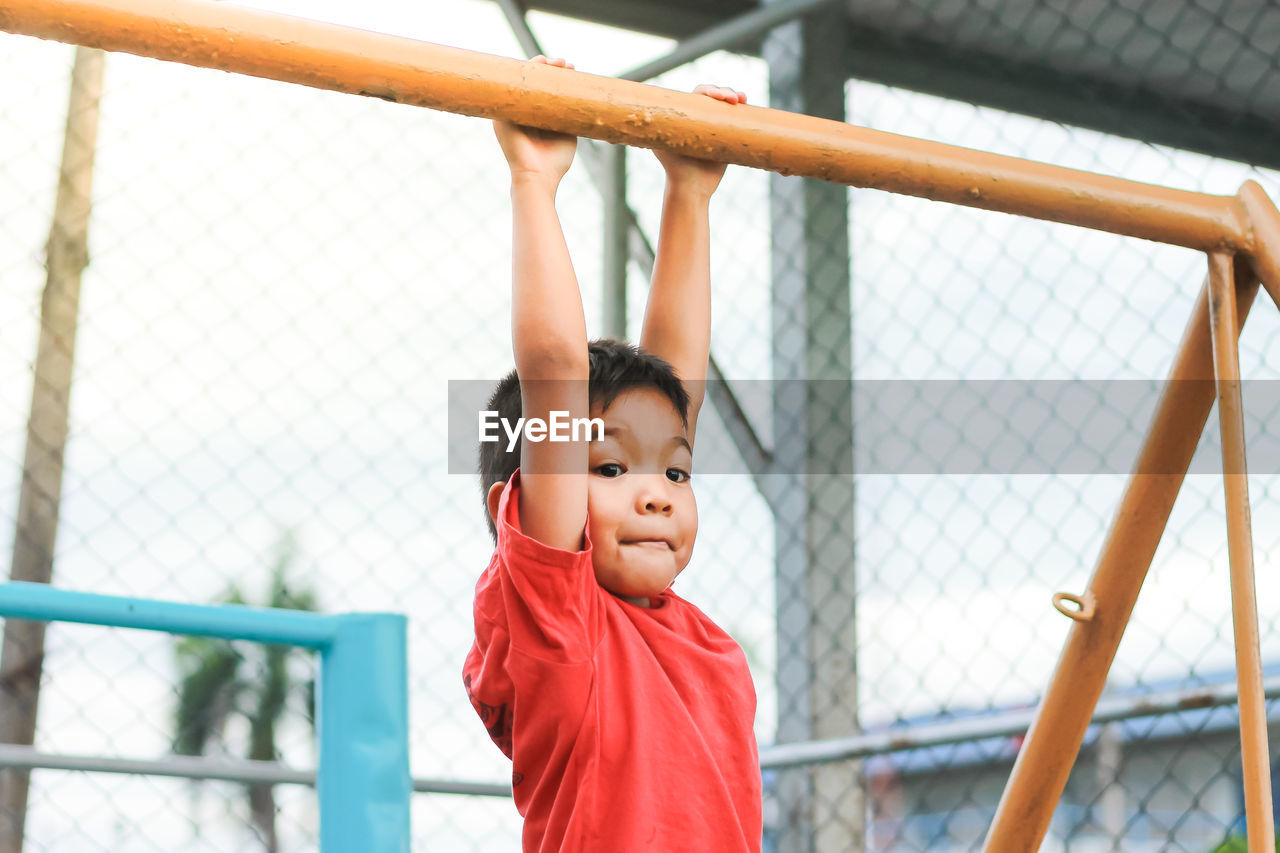 Boy hanging on metal in playground