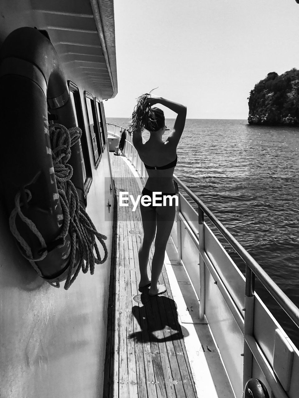 Sensuous young woman in bikini standing on boat deck