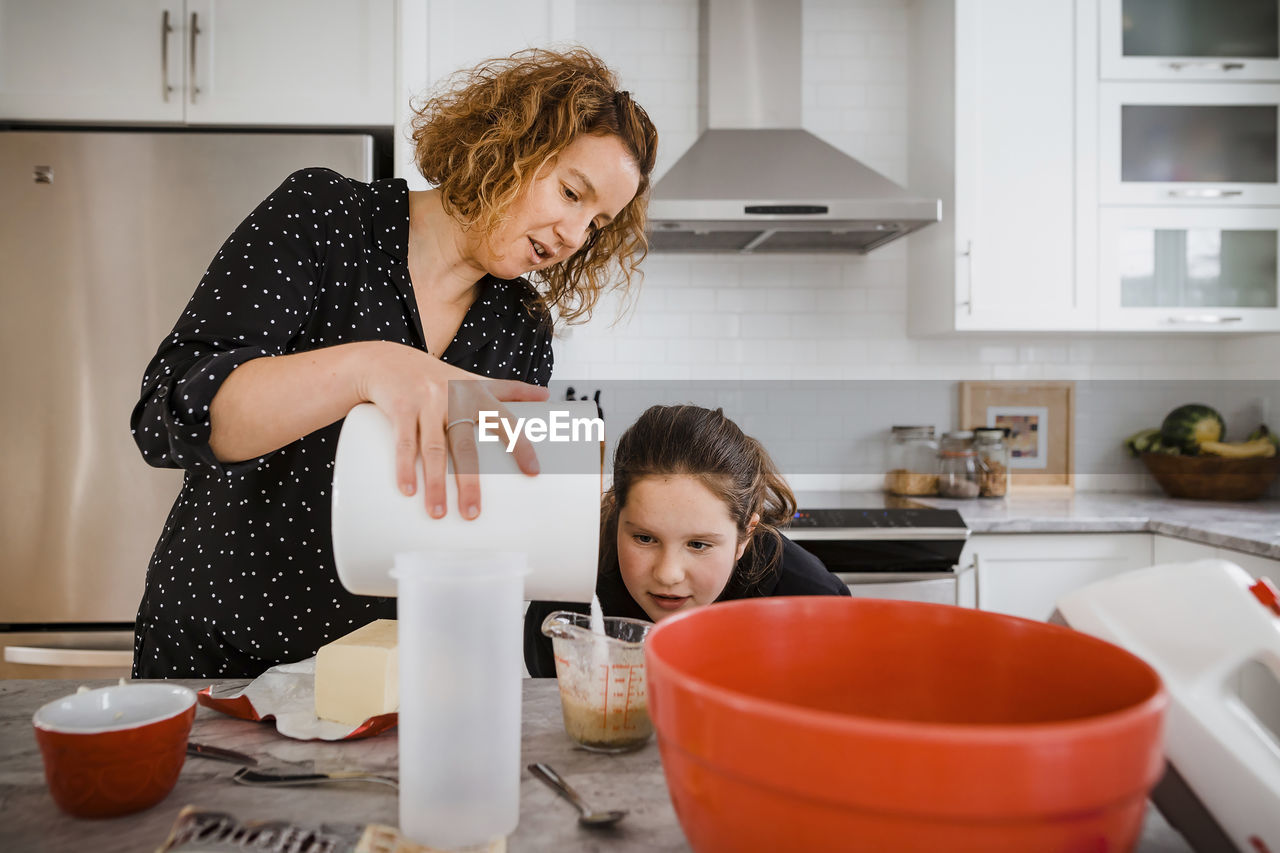 Mother teaching daughter to cook in kitchen at home