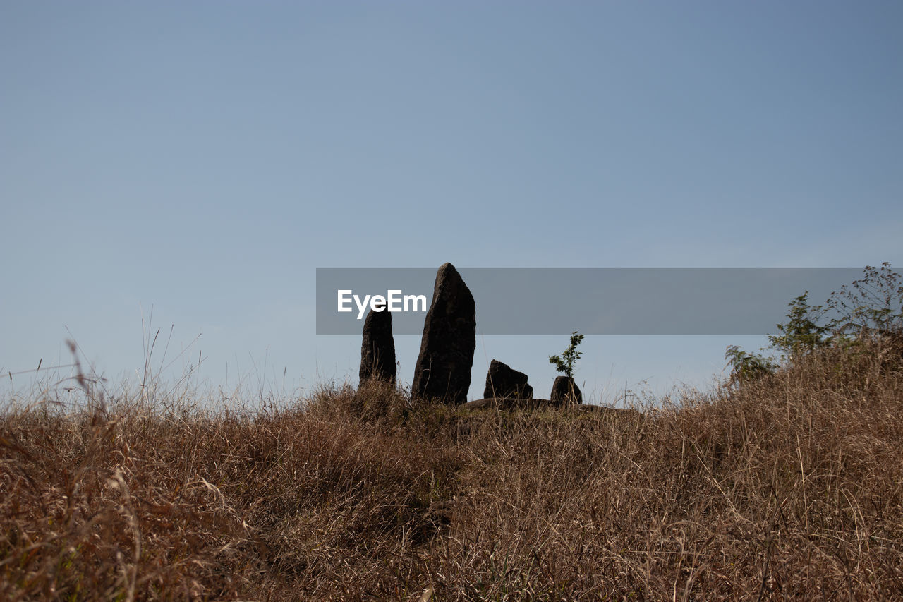 Standing sacred stone monoliths with bright blue sky and grass from a different perspective