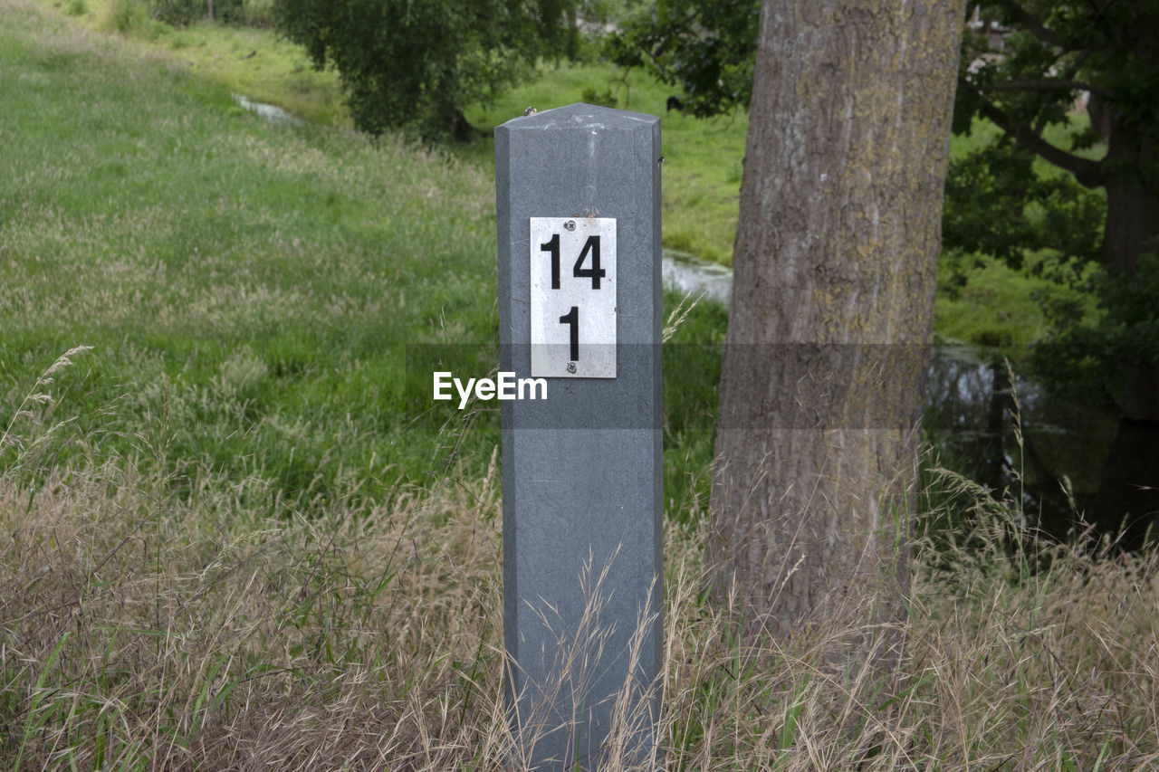 INFORMATION SIGN ON FIELD BY TREES