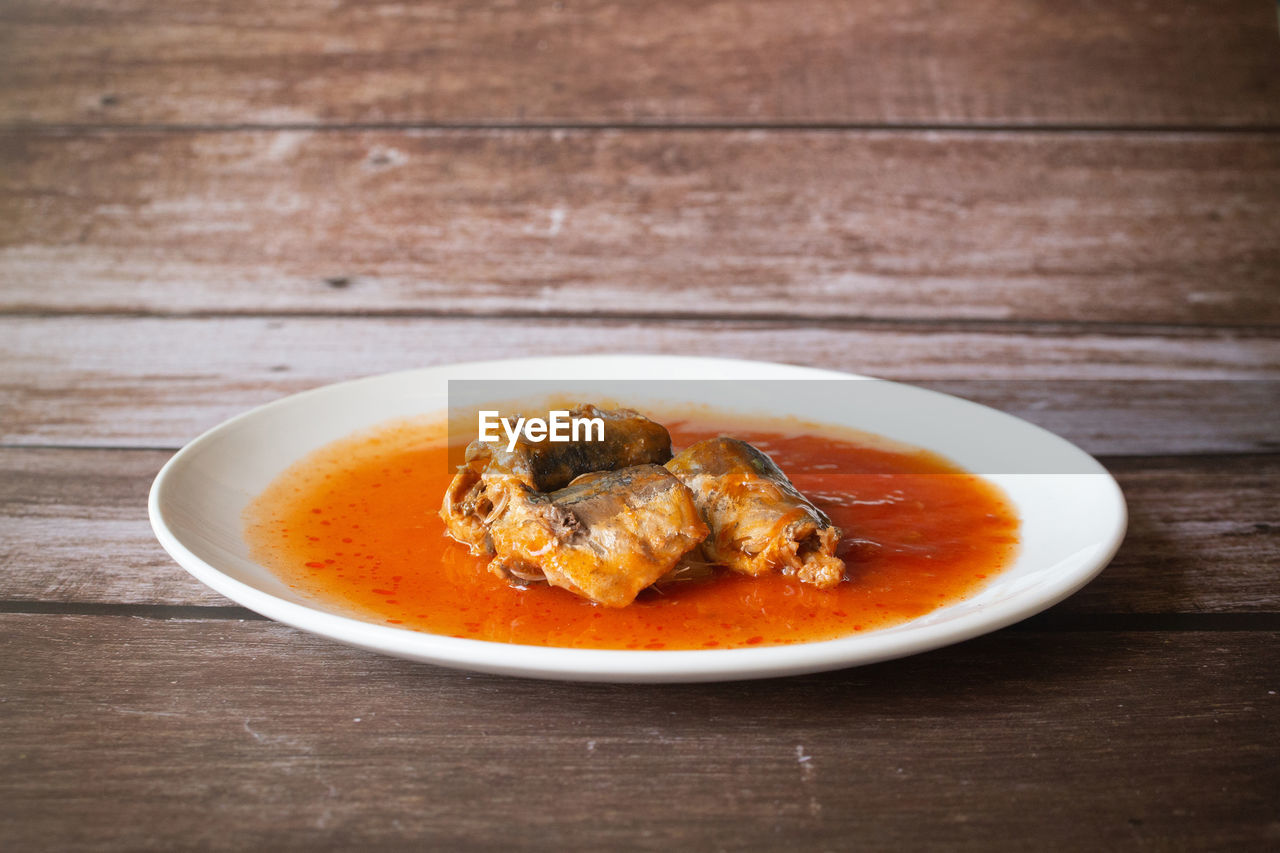 Canned fish in tomato sauce on wood background, sardines, mackerel, thai fast food