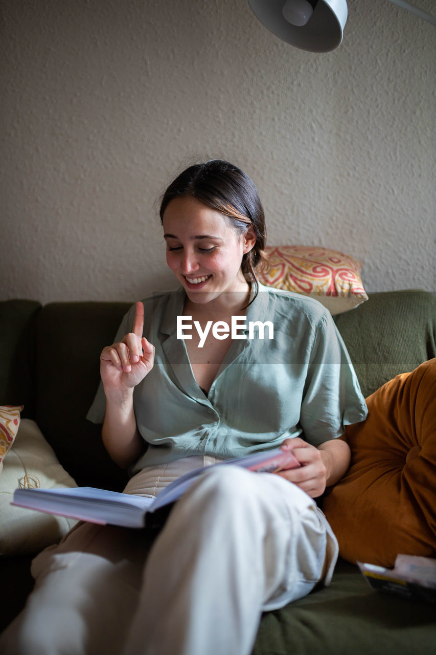 Female sitting on sofa in living room and reading a book