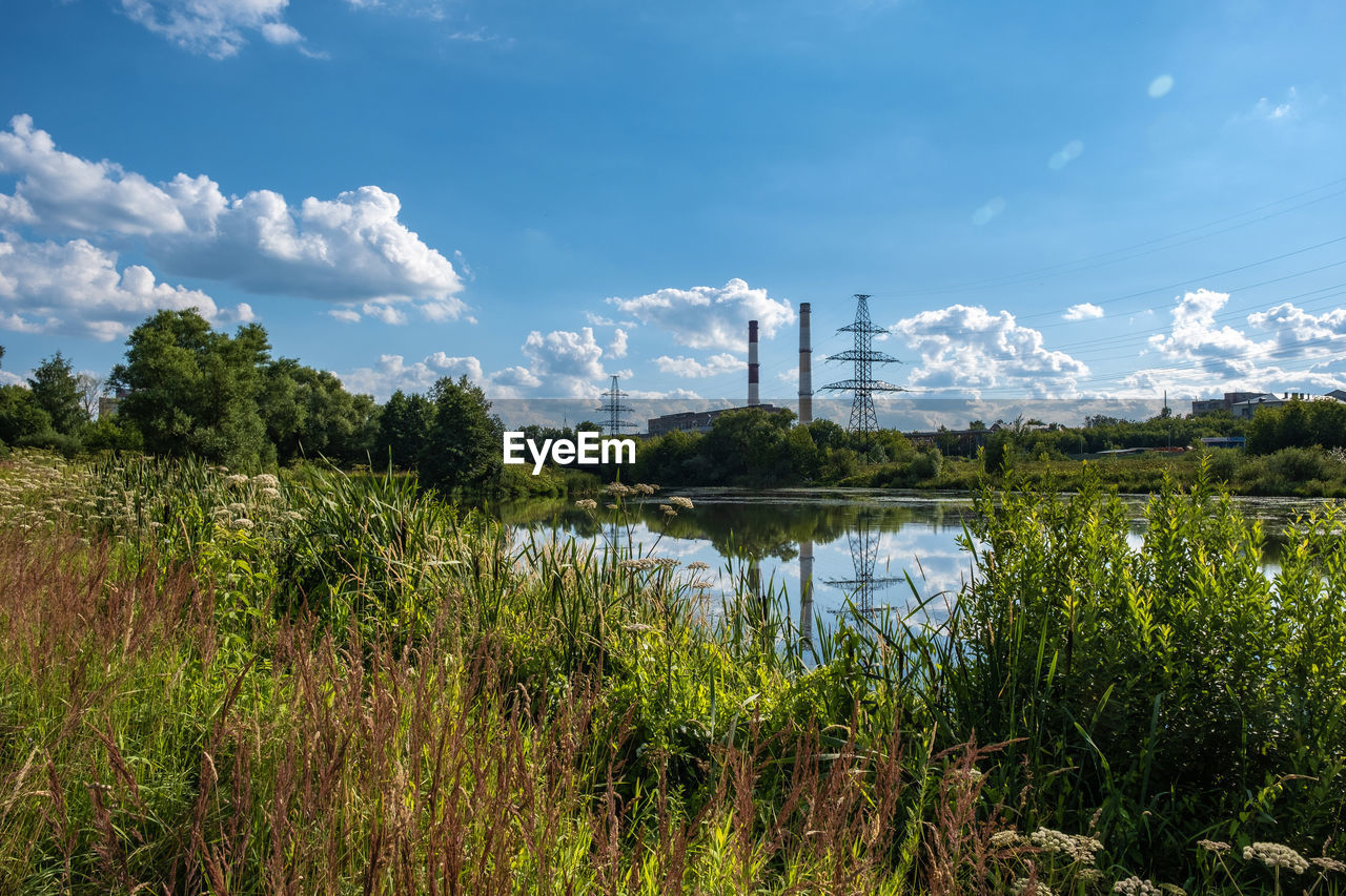 Reflection of a power line and two tall pipes in the uvod river on a sunny summer day.