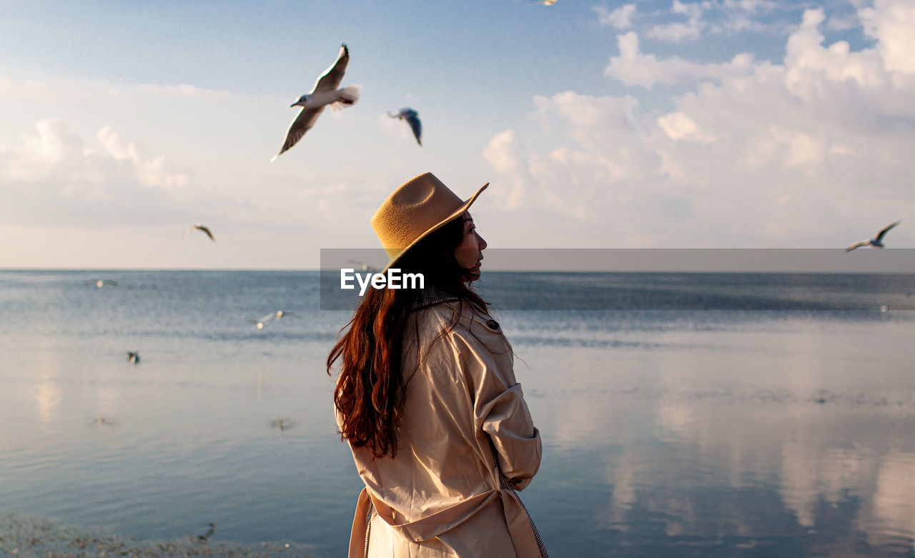 Back view of woman on pier with sea birds