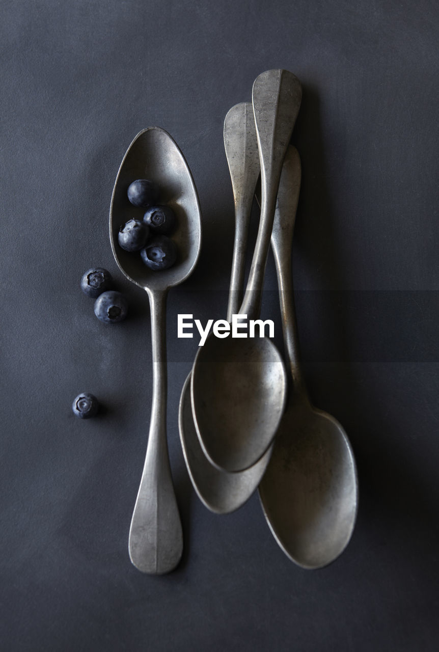 Blueberries with old spoons on tabletop