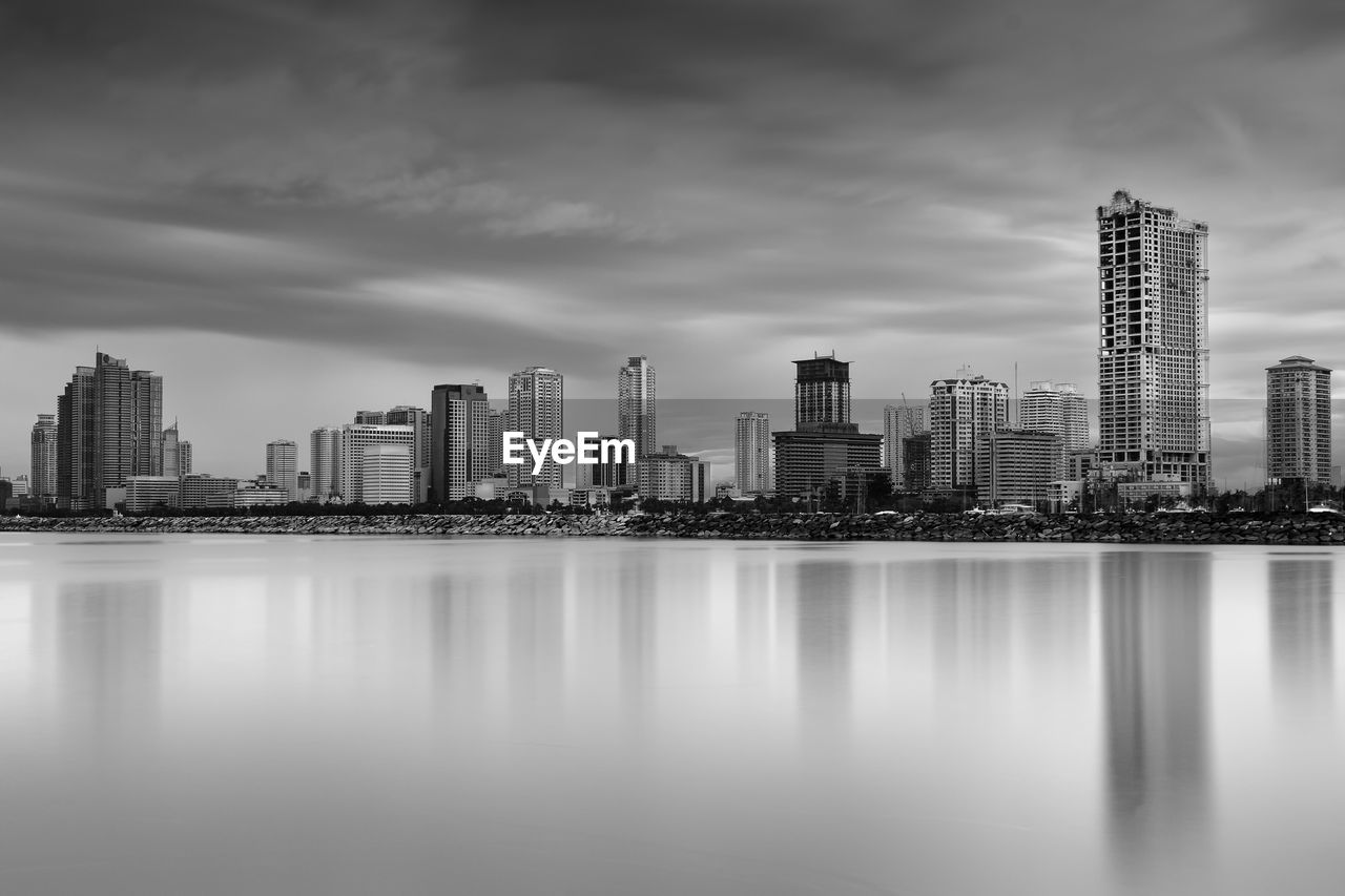 Scenic view of sea by city against cloudy sky