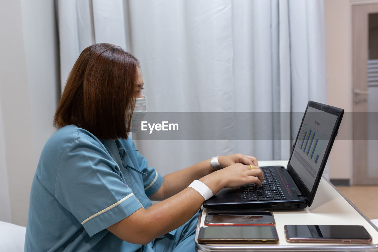 Illness asian patient women still  using laptop for working hard  in patient room of hospital