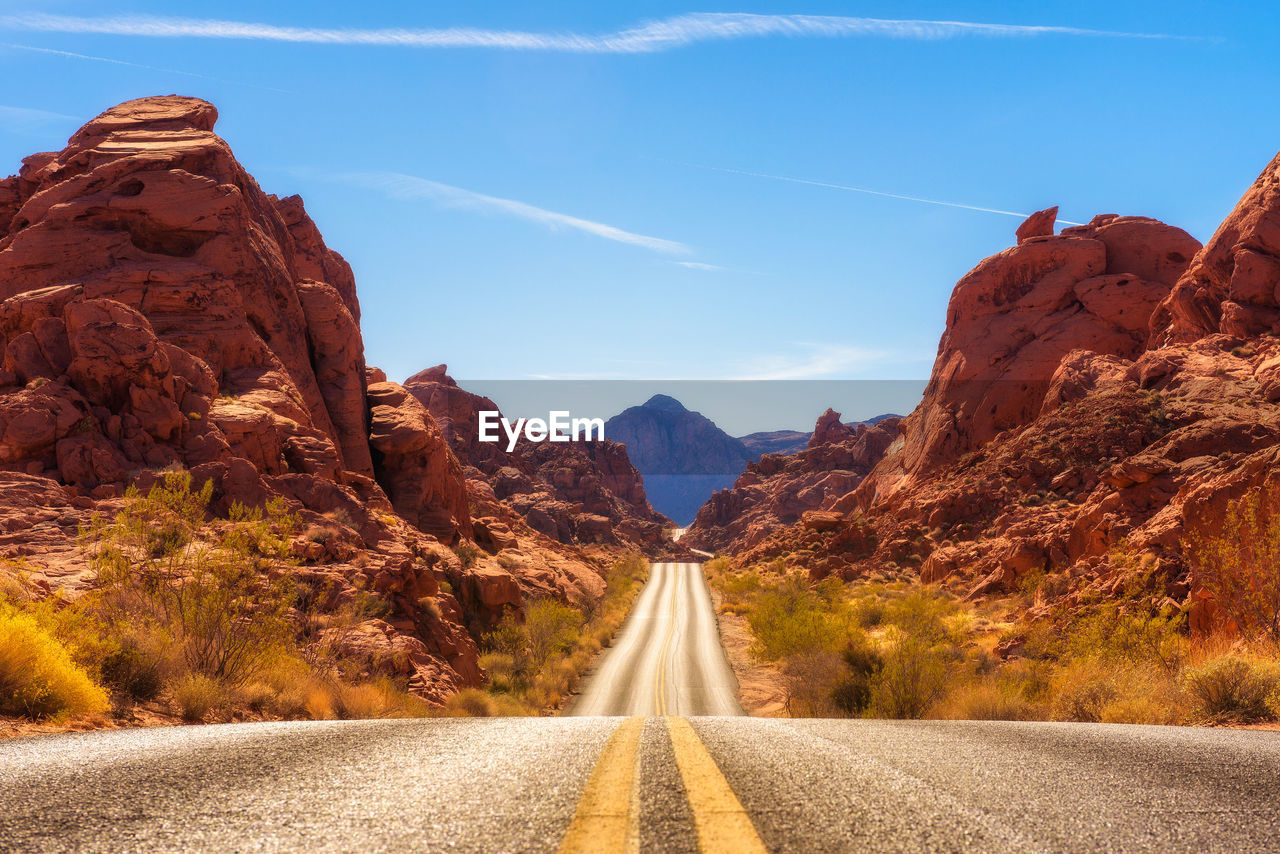 ROAD AMIDST ROCKS AGAINST MOUNTAINS