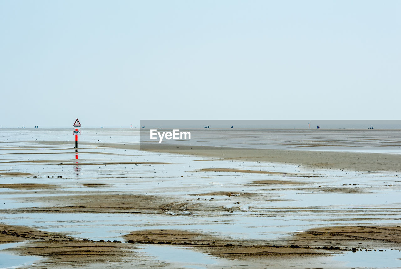 PERSON STANDING ON BEACH AGAINST CLEAR SKY