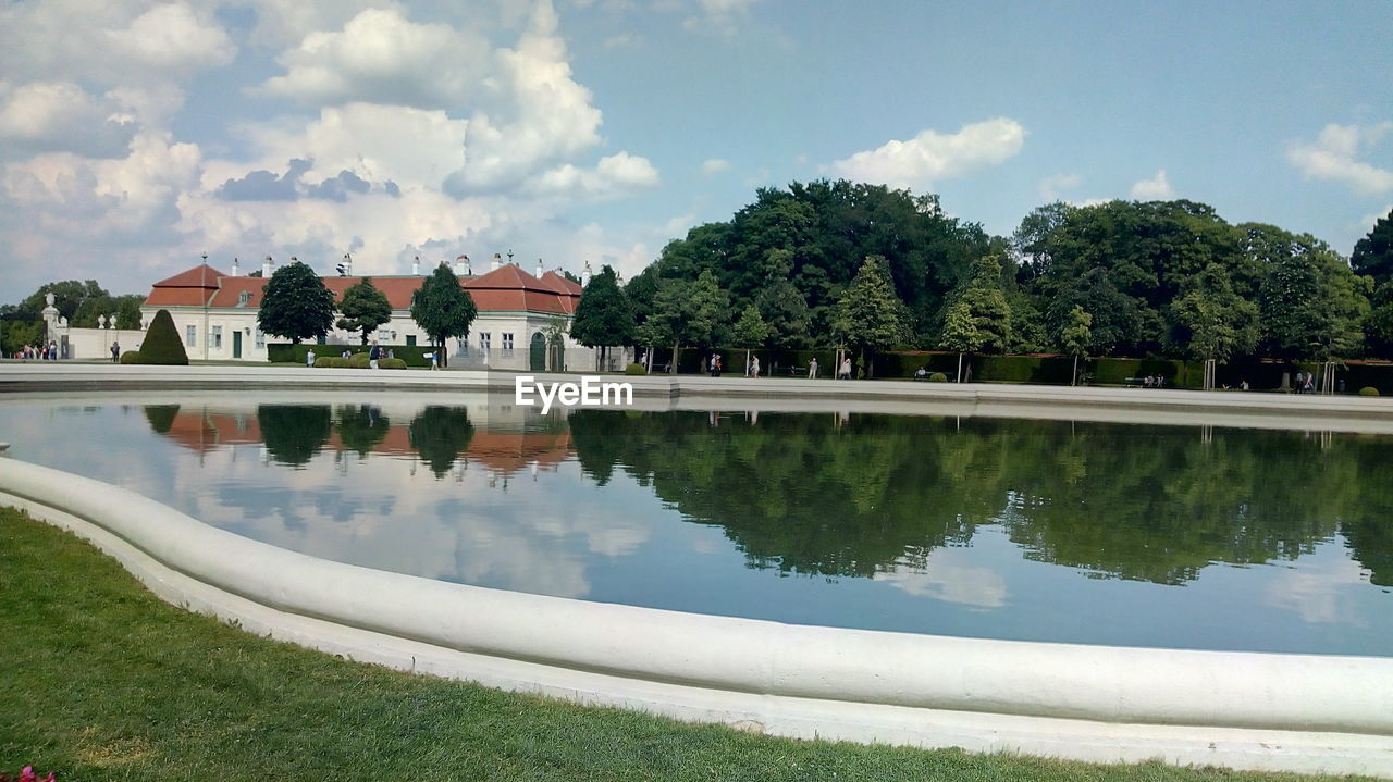 REFLECTION OF TREES AND BUILDINGS IN LAKE AGAINST SKY