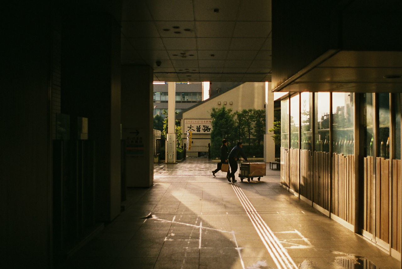 MAN WALKING AMIDST BUILDINGS IN CITY