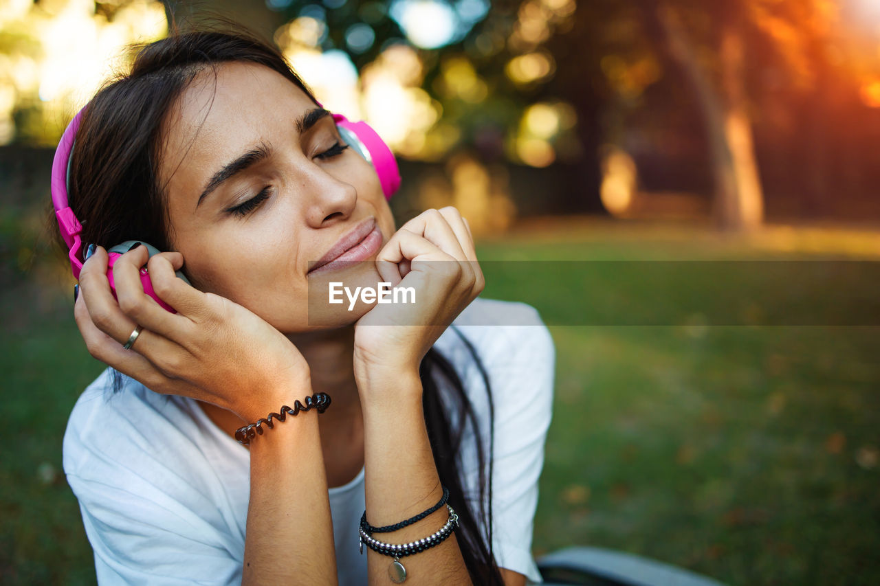 Young woman with headphone on grass outdoors