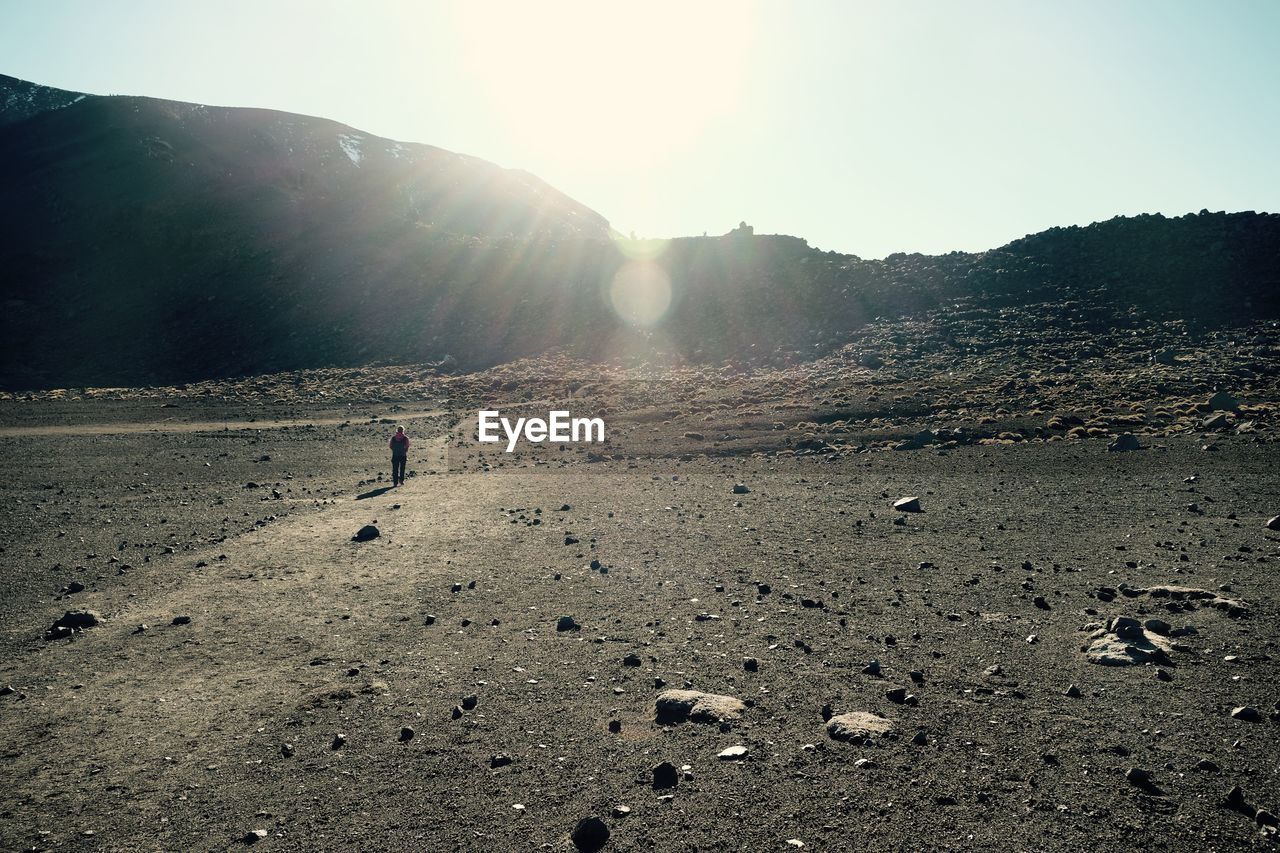 REAR VIEW OF MAN WALKING ON MOUNTAIN